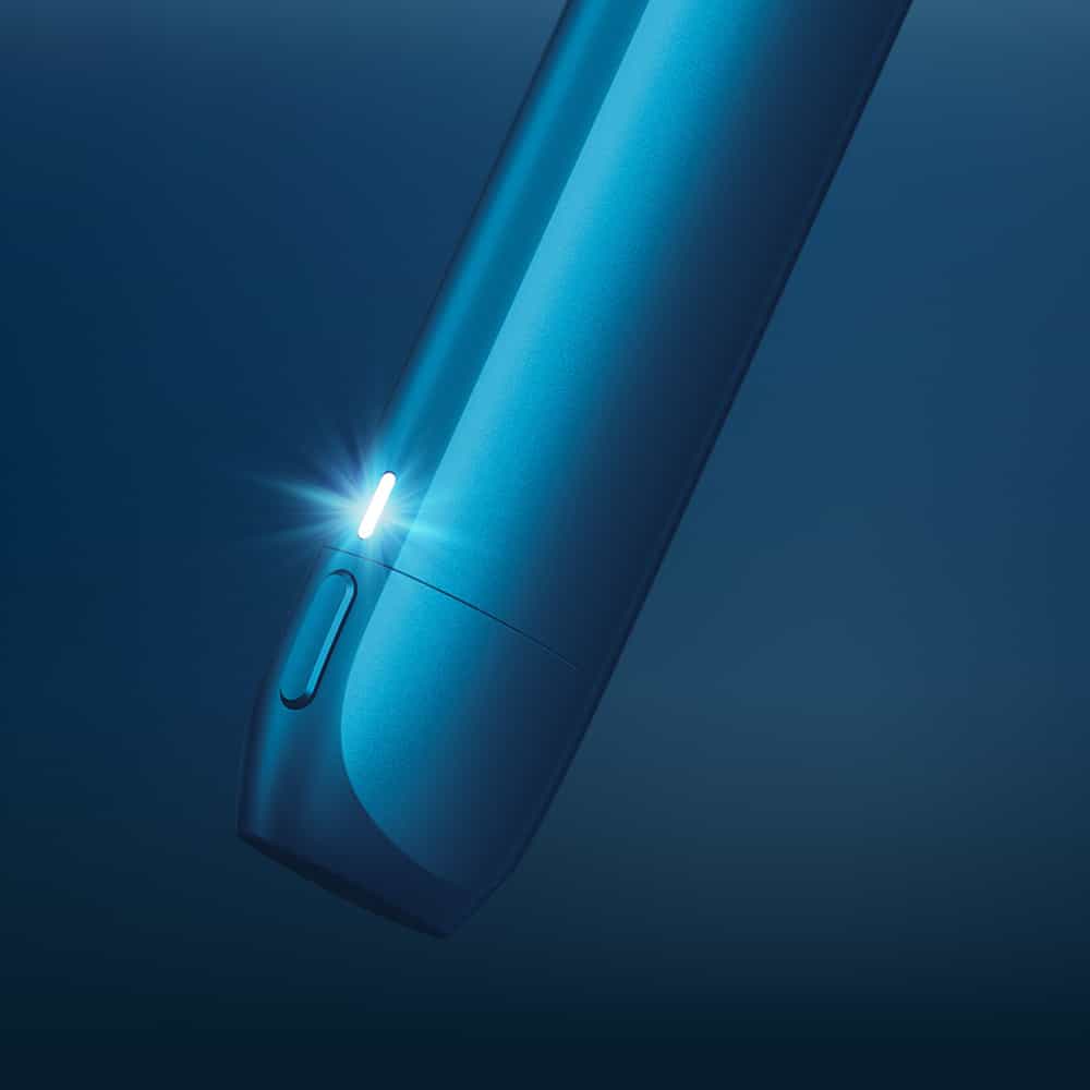 Vuse | Gros plan sur un appareil électronique bleu doté d'un voyant lumineux, aux bords lisses et arrondis et muni d'un bouton sur le côté, sur fond bleu foncé. | Cigarettes Electroniques et Recharges